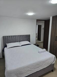 a bedroom with a large bed with white sheets at Posada Los Geranios in Duitama