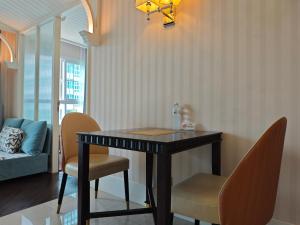 a dining table and chairs in a living room at Grand Florida芭提雅带免费游泳池温泉桑拿浴和健身房瑜伽室私家海滩公寓E206 in Na Jomtien