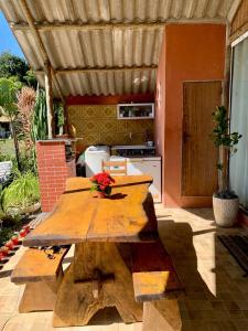 a wooden table in a patio with a kitchen at Chácara Recanto dos Fortes in Casimiro de Abreu