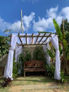 a wooden pergola with a bench in the grass at Chácara Recanto dos Fortes in Casimiro de Abreu +42 photos