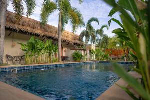 a swimming pool in front of a house with palm trees at TALI BOUTIQUE Hotel in Ao Nang Beach