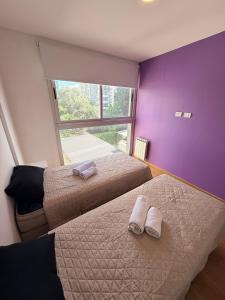 2 camas en una habitación con paredes de color púrpura y ventana en Las Lomitas Torre London, en Lomas de Zamora
