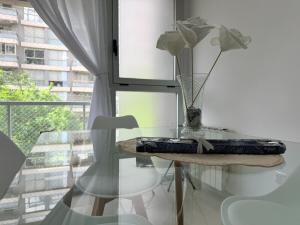 una mesa de cristal con un jarrón con flores. en Las Lomitas Torre London, en Lomas de Zamora 14 fotos más