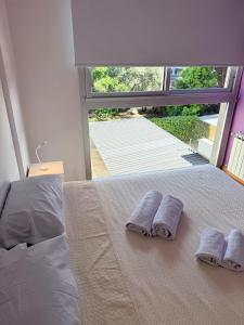 Dos toallas en una cama en un dormitorio con ventana. en Las Lomitas Torre London, en Lomas de Zamora