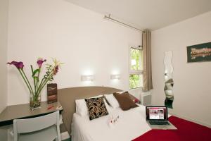 a room with a bed and a laptop on a table at Hotel Cerise Nancy in Nancy