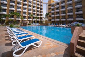 a swimming pool with lounge chairs and a hotel at Hotel Margarita Dynasty in Porlamar +54 photos
