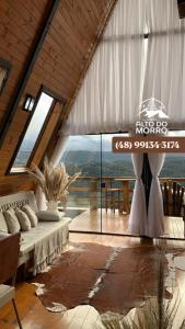 uma sala de estar com uma cama e uma janela grande em Chales alto do morro 1, conforto e vista privilegiada em Rancho Queimado