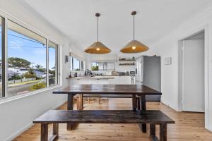cocina con mesa de madera y 2 bancos en Harbour Mist Hideaway - Where Coast Meets Calm, en Ulladulla