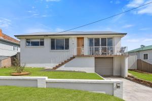 Casa blanca con balcón y césped en Harbour Mist Hideaway - Where Coast Meets Calm, en Ulladulla