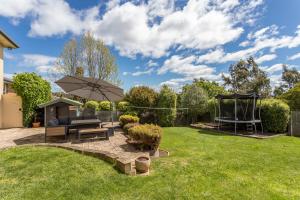 a garden with a bench and an umbrella at Bonnie Belle, Norwood in Kings Meadows