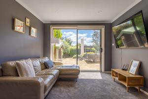 a living room with a couch and a sliding glass door at Bonnie Belle, Norwood in Kings Meadows