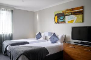 a hotel room with two beds and a flat screen tv at Crest on Barkly Hotel in Melbourne