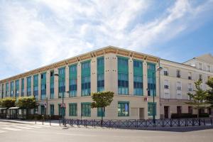 een groot wit gebouw met blauwe ramen aan een straat bij Séjours & Affaires Serris Rive Gauche in Serris