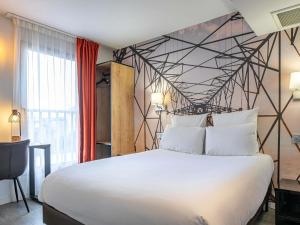 a bedroom with a large white bed with a geometric wall at Mercure Paris Malakoff Parc des Expositions in Malakoff