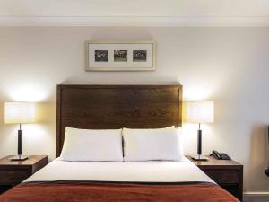 a bed in a hotel room with two lamps at Mercure Haydock Hotel in Haydock