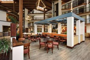 a restaurant with tables and chairs and a bar at Radisson Hotel Lenexa Overland Park in Lenexa