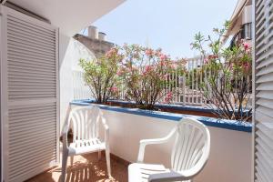 two white chairs sitting on a balcony with flowers at Viva Sitges - Sitges Central Apartment in Sitges