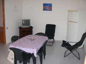 una sala da pranzo con tavolo, sedie e TV di Casa Vacanze Serena ad Alcamo Marina