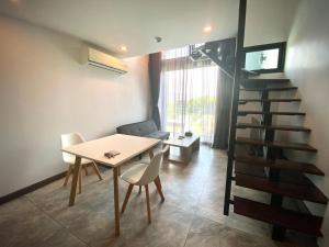 a dining room with a table and a spiral staircase at utopia naihan in Phuket Town