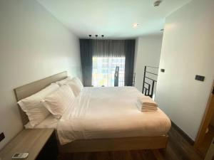 a bedroom with a bed with white sheets and a window at utopia naihan in Phuket Town