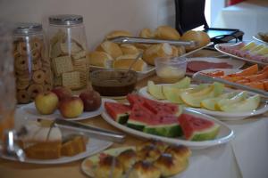 a table topped with plates of food with fruits and vegetables at Hotel Sinhozinho in Coxim