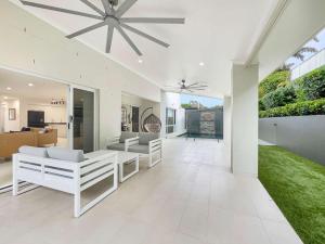 a living room with white furniture and a ceiling fan at Relaxed Luxury for Families by the Beach in Buddina