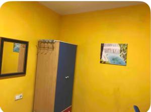 a room with a yellow wall with a wooden cabinet at Casa con encanto con perritos in San Juan de Alicante
