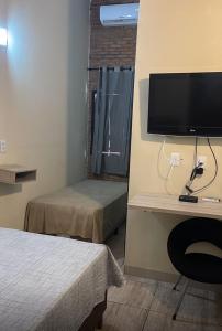 Una habitación con un escritorio con televisión y una cama. en BR 153 Hotel, en Hidrolândia
