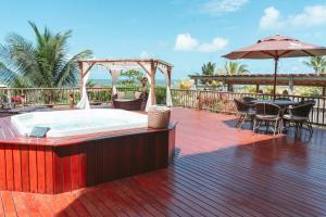 a hot tub on a deck with a table and chairs at Vila Katuara in Santa Cruz Cabrália
