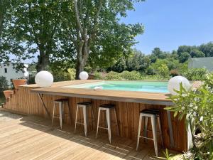 a backyard bar with stools and a swimming pool at Chemin des Dames - Gite in Montauban