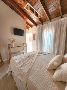 a bedroom with a large white bed with a window at LA CURVA Casa de Playa in Villa Gesell