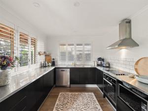 eine große Küche mit schwarzen Schränken und weißen Wänden in der Unterkunft Bindi Place - Charming House in Margaret River in Margaret River Town