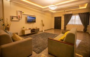 a living room with two couches and a tv at Agape Villa in Takoradi