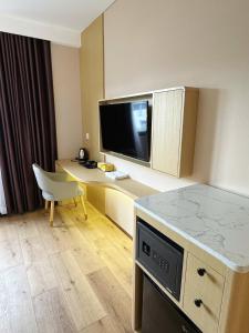 a hotel room with a desk with a tv and a table at ELONG me hotel in Ho Chi Minh City
