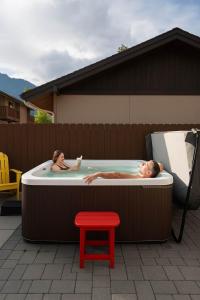 a man and woman in a hot tub with a red stool at Snowcreek Suite - Dogwood - Hot tub - Kitchenette in Leavenworth