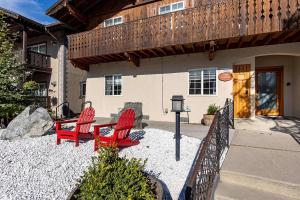 two red chairs and a table in front of a building at Snowcreek Suite - Dogwood - Hot tub - Kitchenette in Leavenworth
