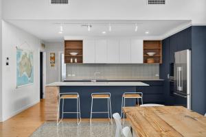 a kitchen with blue walls and a wooden table and stools at Riverside Retreat - Waterfront - Hindmarsh Island - Linen Included in Hindmarsh Island