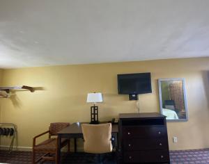 a hotel room with a desk and a tv on the wall at Innkeeper Motel Hamel in Hamel