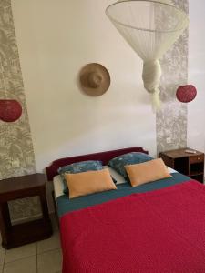 a bedroom with a bed with a red blanket and pillows at Les Manguiers in Deshaies