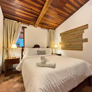 a bedroom with a white bed with a wooden ceiling at Hacienda Cascanueces in Villa de Leyva