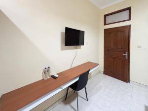 a room with a wooden desk with a television on the wall at Urbanview Noja Guest House near Living World Denpasar in Denpasar