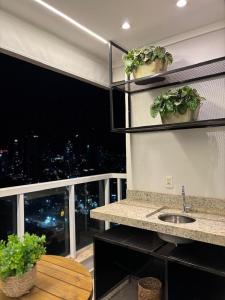 eine Küche mit Spüle und einem Fenster mit Pflanzen in der Unterkunft Flat | Linda vista | Ao lado do Goiânia Shopping in Goiânia + 17 Fotos
