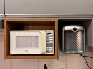 eine Mikrowelle und ein Fernseher in der Küche in der Unterkunft Flat | Linda vista | Ao lado do Goiânia Shopping in Goiânia