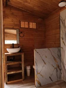 Habitación de madera con baño con lavabo. en Glamping Entre Nopales, Villa de Leyva, en Sáchica