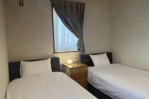 two beds in a small room with a window at お休み処おおはま in Yomitan