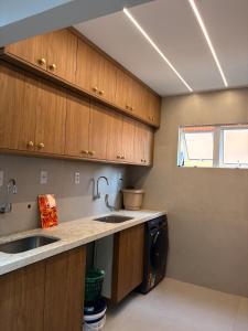 een keuken met houten kasten, een spoelbak en een vaatwasser bij Apartment - Metropolitan Region of Belém in Ananindeua