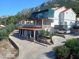 a large white house with a car parked in a driveway at Comfort One Bedroom Apartment with Terrace and Sea view in Sveta Nedelja