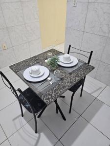 累西腓Casa Recife Conforto 6的一张桌子、两把椅子和一张桌子,上面有盘子和盘子