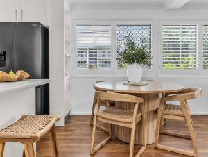 a kitchen with a table and chairs and a refrigerator at Wave Whisperer in Kingscliff
