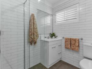 a white bathroom with a sink and a mirror at Wave Whisperer in Kingscliff +12 photos